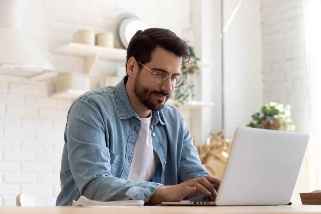 A man uses digital procurement software on a laptop in an office.