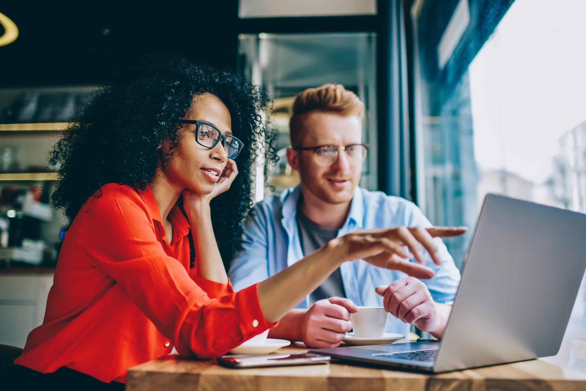 A female procurement employee and a male colleague identify fraud using a laptop.