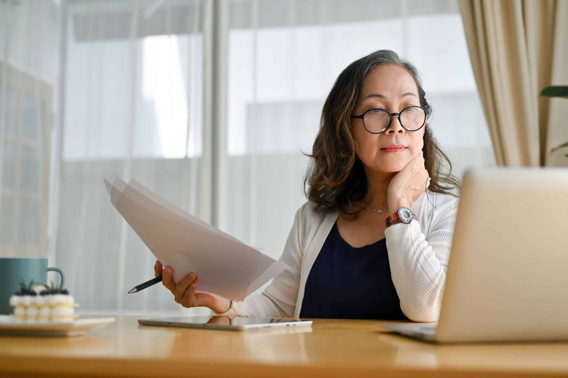 A concentrated middle aged female reviews purchase orders on a laptop.